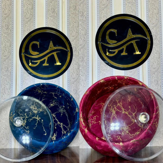 Two marbled bowls, one blue and one pink, with clear lids on a striped background.
